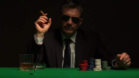 cool gambler playing poker in sunglasses