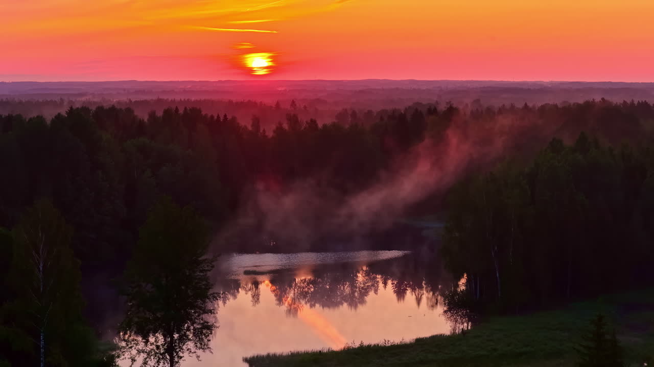 Sunrise on a small cold lake where steam rises. Static view