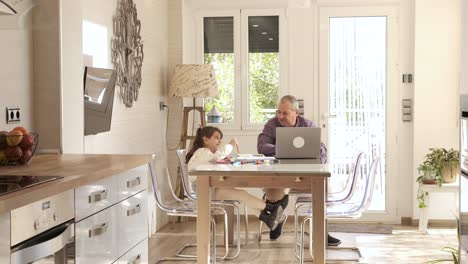 girl playing while her grandfather working next to them