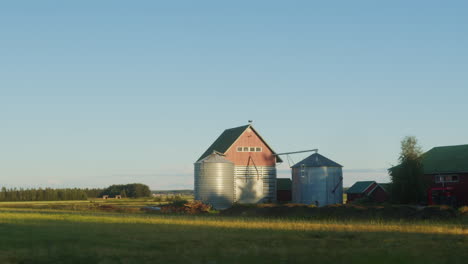 passing grain silos in the finnish countryside during sunset