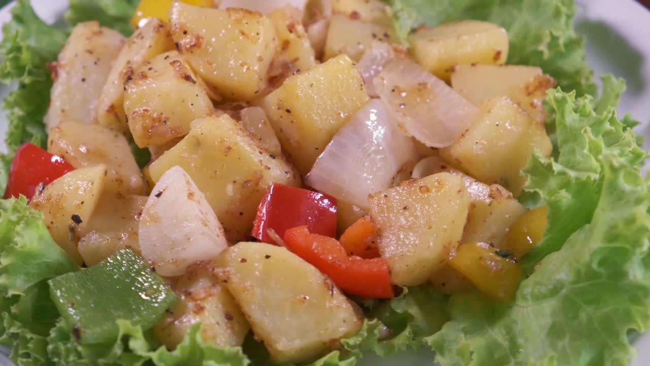 A Delicious Potato Salad with Onions, Red Sliced Peppers and Lettuce on a Rotating Plate with Close Up