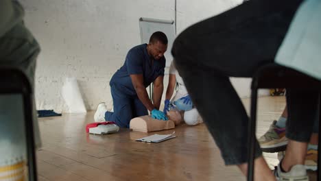 Bottom-view:-A-Black-male-doctor-in-a-blue-uniform-performs-artificial-respiration-for-a-medical-mannequin,-his-assistant-a-female-nurse-in-a-white-uniform-makes-a-mannequin-artificial-respiration-using-an-Anbu-resuscitation-bag