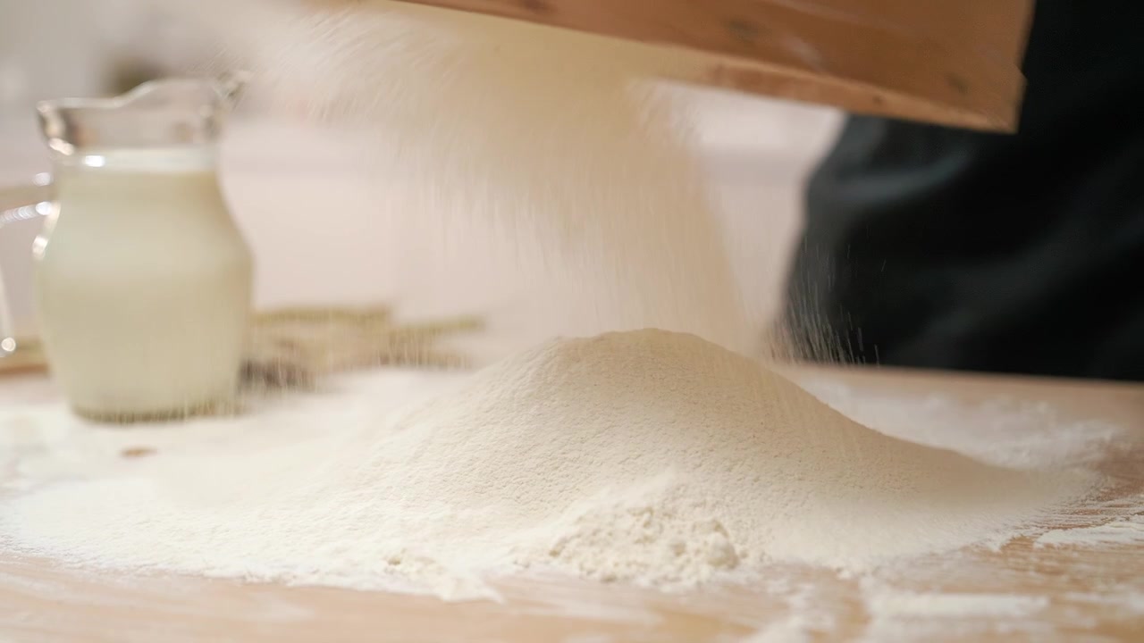 Primo piano di farina bianca setacciata su un tavolo di legno