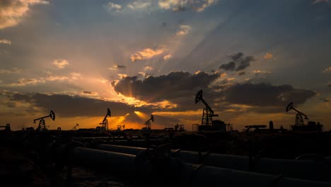 pipeline and working oil pump jacks in a against sunset extracting crude oil. pumping fossil oil is one of the methods of energy generation from renewable energy sources