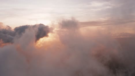 incredible heavenly aerial view flying through light, heaped up and wispy clouds in golden sunset, sunrise revealing sun