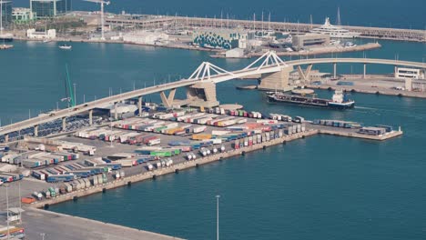 vista aérea del puerto de carga de barcelona: escena de navegación ocupada con contenedores apilados, grandes cargueros y actividad marítima