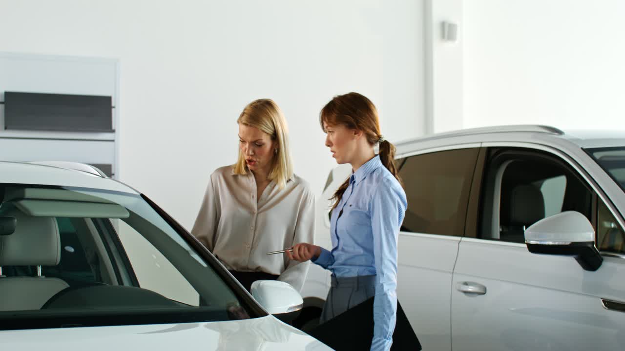 mujeres discutiendo un coche en una sala de exposiciones