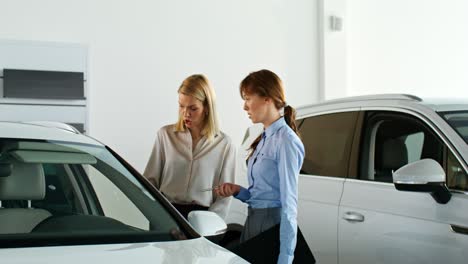 women discussing a car in a showroom