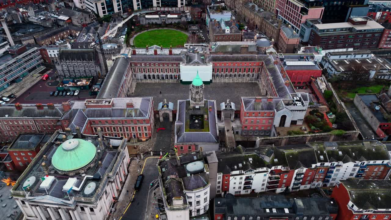 Droneopptak over Dublin Castle i sentrum av Dublin i Irland, med travle gater nedenfor med biler og busser og turister som spaserer rundt i det irske bybildet på en overskyet dag om vinteren