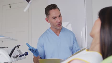 caucasian male dentist talking and preparing female patient at modern dental clinic