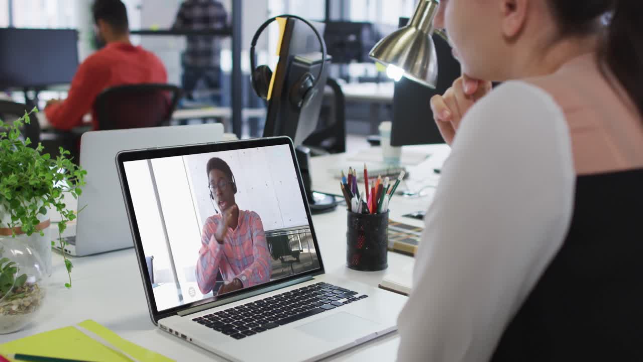 Caucasian businesswoman sitting at desk using laptop having video call with male colleague