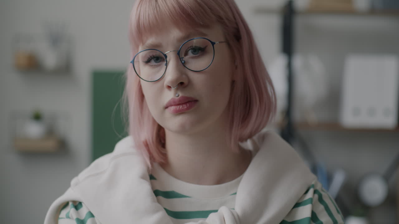 Young woman with pink hair and glasses
