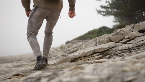 male hiker in outdoor clothes runs down white rocky hill, slow motion