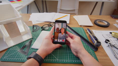 POV-Shot-Of-Female-Architect-Working-In-Office-Having-Virtual-Meeting-With-Couple-On-Mobile-Phone