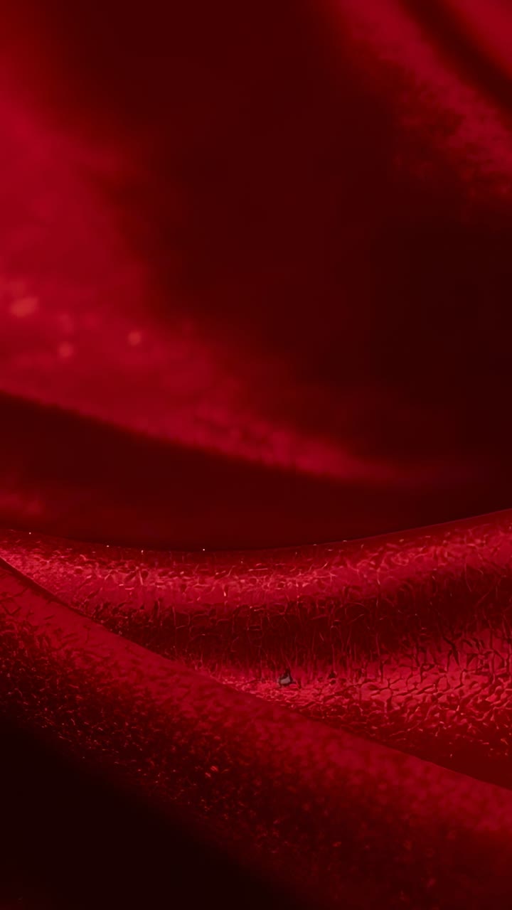 Vertical video: Shifting lighting creating gentle highlights on red velvet fabric in studio