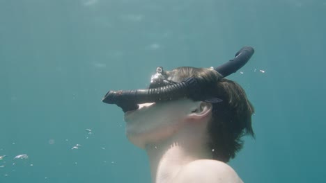 Close-up-shot-of-Man-with-googles-snorkeling-in-clear-ocean-water-and-watching-sunlight-on-surface,slow-motion