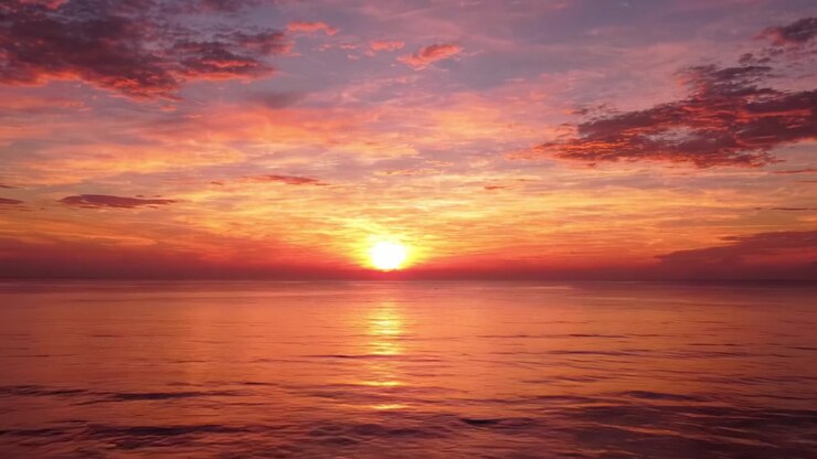 A Serene Sunset Over the Ocean: Embracing the Mellow Hues of Twilight as the Sun Dips Below the Horizon, Reflecting Its Warm Colors on the Calm Water