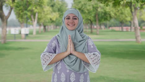 happy muslim woman doing namaste in park