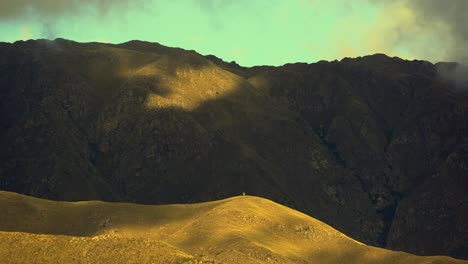 pleasant view of clouds and shadows moving over the mountains during sunset. bright yellow hill with a landmark at the top. timelapse in 4k. merlo, san luis, argentina.