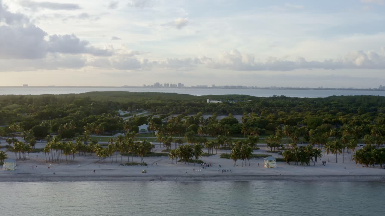 Rising aerial drone shot of the beautiful tropical beach surrounded by palm trees on Crandon Park in Key Biscayne outside of Miami, Florida on a warm sunny summer evening
