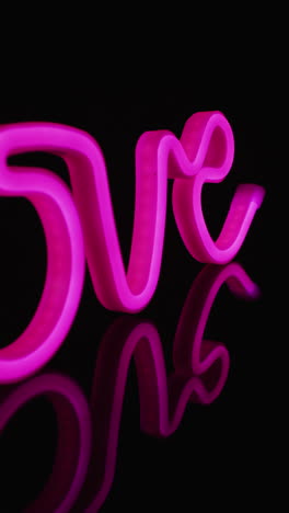 video vertical de luces de neón rosas formando amor sobre un fondo negro