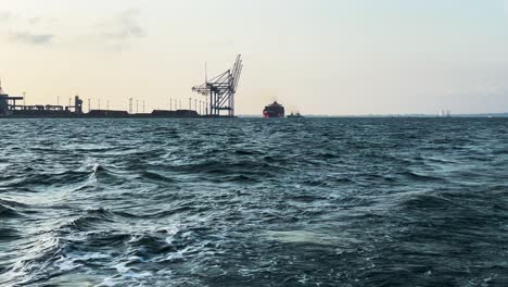 Welliges-Wasser-Des-Schwarzen-Meeres-Mit-Blick-Auf-Hafenkräne-Von-Einem-Segelboot-In-Odesa,-Ukraine