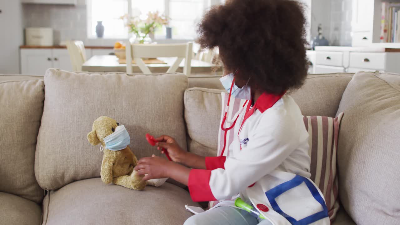 chica afroamericana jugando al médico y al paciente con su oso de peluche