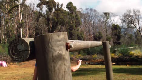 Woman-crawling-under-the-hurdle-during-obstacle-course