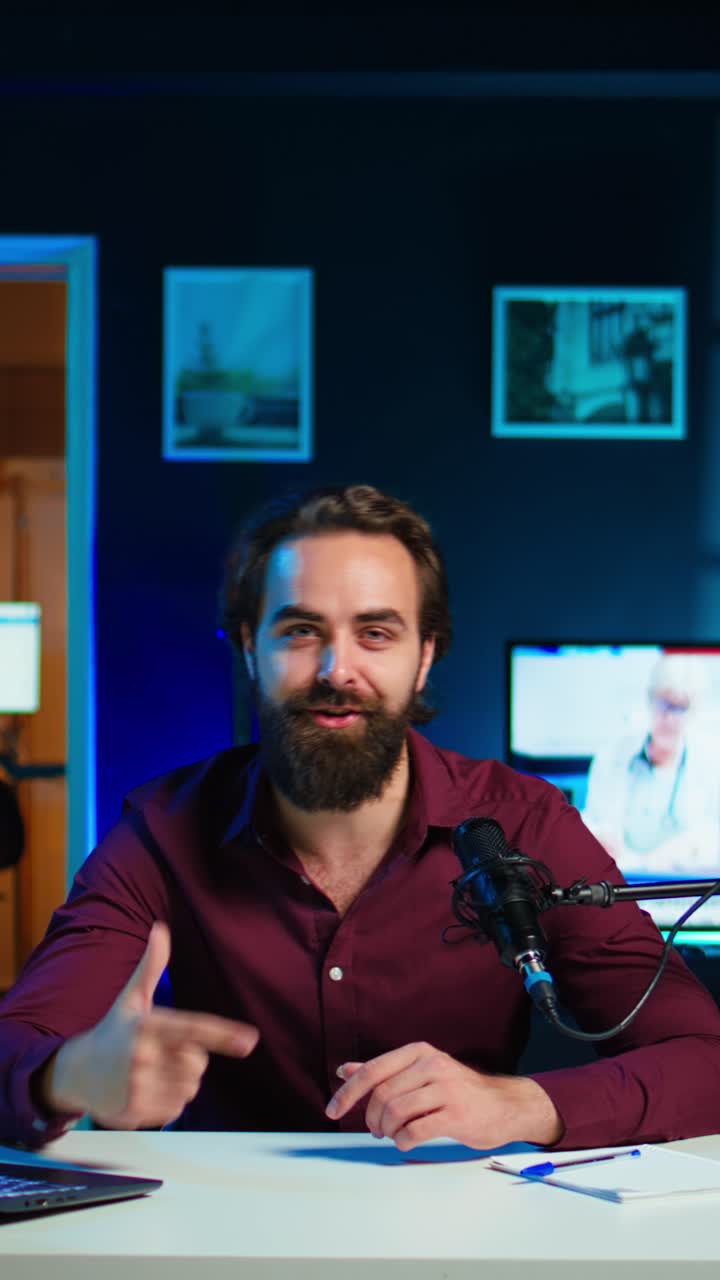 Video verticale. Uomo in uno studio domestico illuminato al neon che utilizza attrezzature per le riprese di vlog
