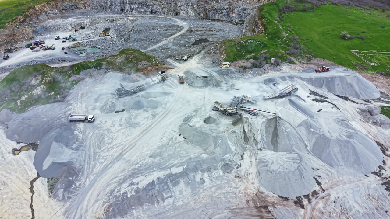 Cantera de granito con maquinaria y trabajadores en un sitio de construcción durante operaciones diurnas.