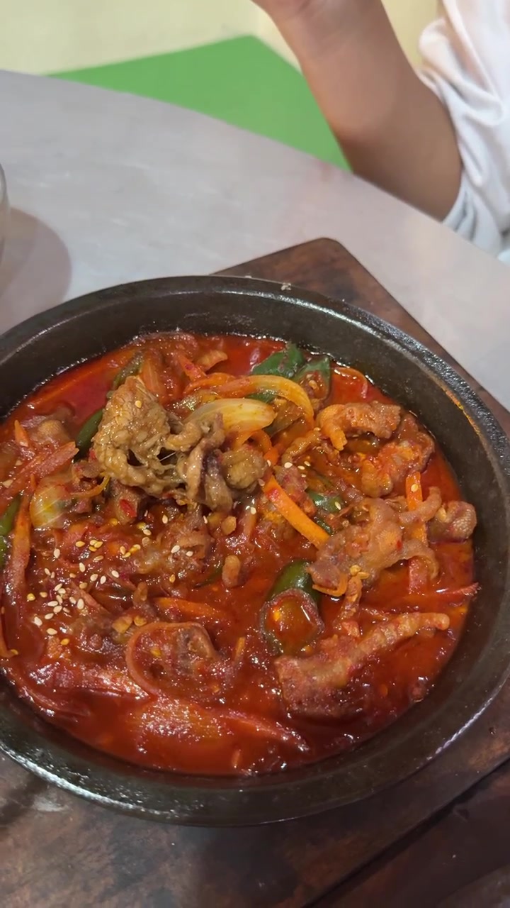 Seseorang Makan Ceker Ayam Pedas Korea dengan Sumpit