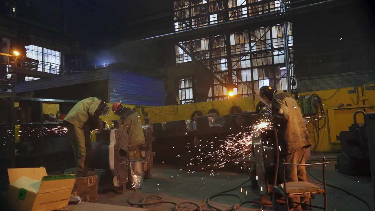 Metal Workers Welding in a Factory at Night