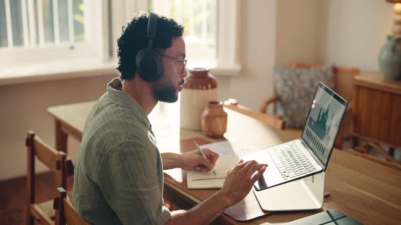 Man in Headphones Working on Laptop and Writing Notes at Home