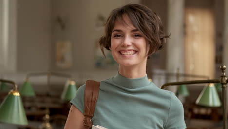 young female student smiling at camera in library