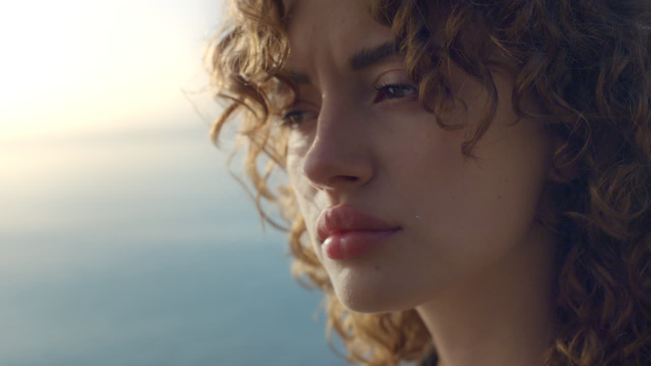 Ragazza sognante che guarda altrove in spiaggia all'alba. Donna calma in posa davanti alla fotocamera.