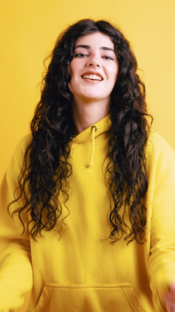 Woman in yellow hoodie with curly hair