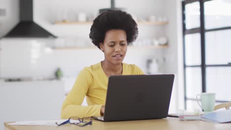 Glückliche-Afroamerikanische-Frau,-Die-Am-Tisch-Sitzt-Und-Einen-Laptop-Benutzt