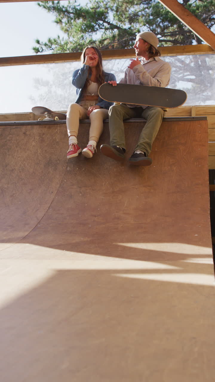 video vertical de mujeres y hombres caucásicos patinando en un parque de patinaje