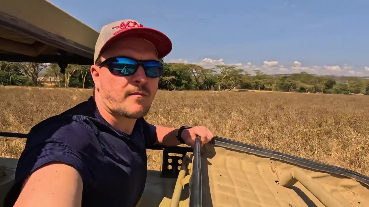 Caucasian man on adventure trip exploring Lake Nakuru savanna in a jeep.