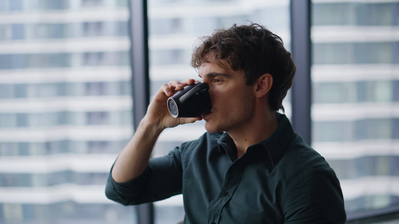 Thoughtful ceo drinking coffee sitting by office panoramic window closeup