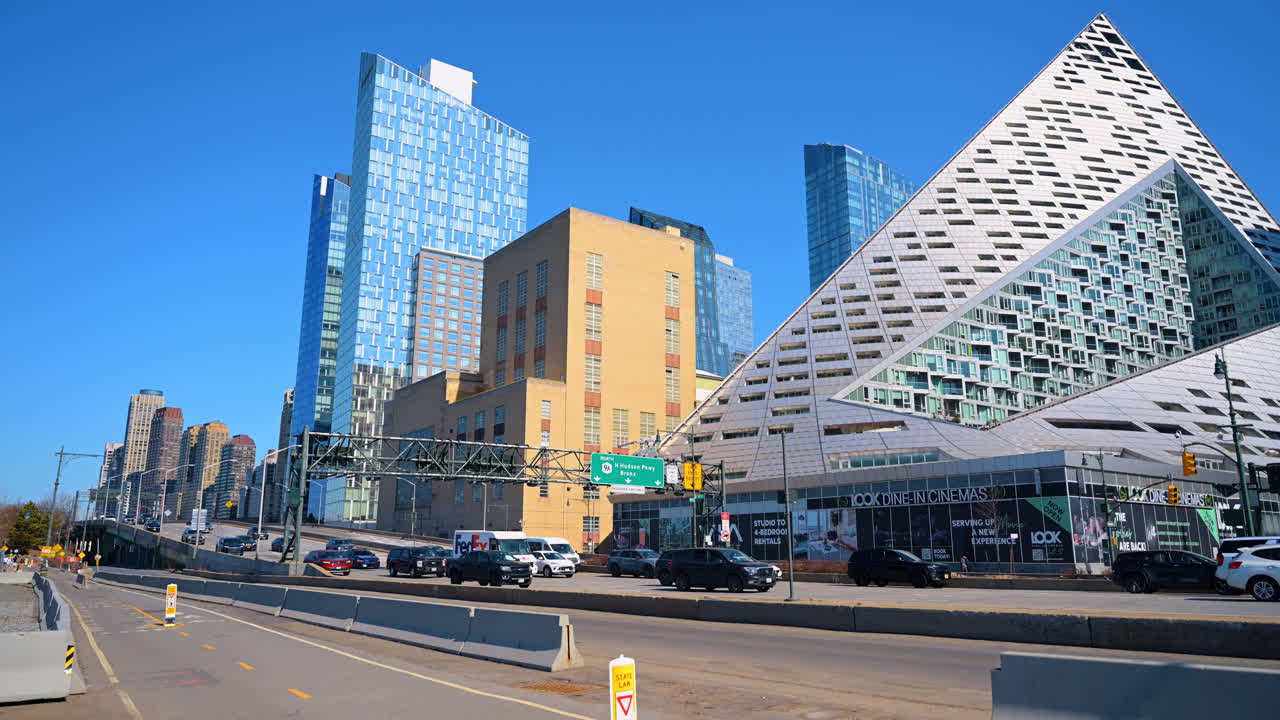 New York, USA, 14 marzo 2026: Architettura triangolare moderna e grattacieli sulla West Side Highway. Edificio residenziale unico a forma di piramide e torri di vetro sotto un cielo azzurro limpido.