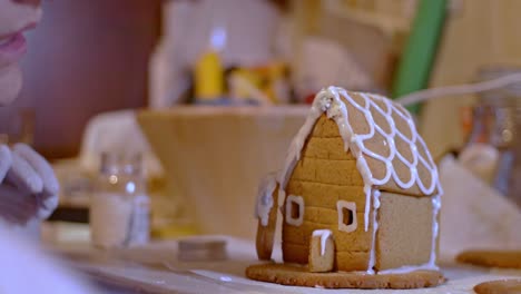 close up on caucasian woman, staring and preparing a gingerbread cookies house 4k