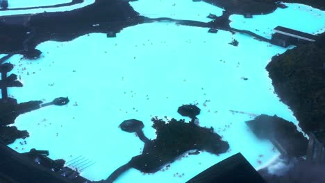 Aerial-View-Of-Blue-Lagoon-With-Tiny-Images-Of-People-Enjoying-The-Geothermal-Bath-Near-Reykjavik,-Iceland