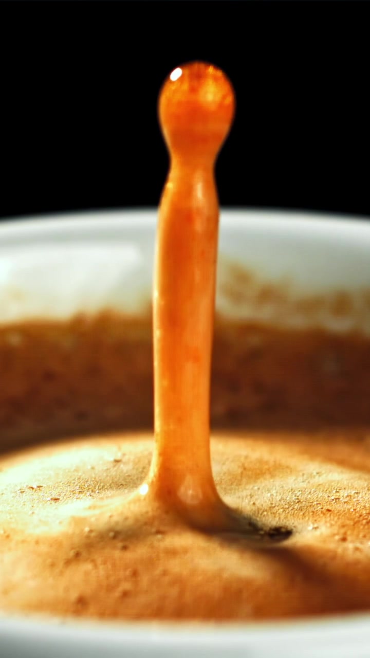 Movimento rallentato di una goccia di caffè che si tuffa nella crema dell'espresso