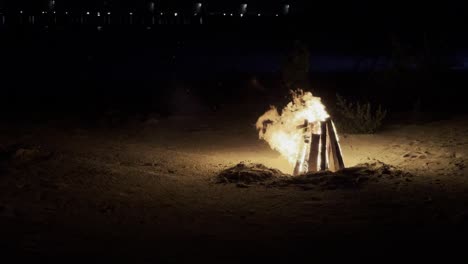 experimente el encanto de la noche de las maldivas: sienta el calor de una fascinante hoguera en la playa mientras proyecta un resplandor fascinante sobre las majestuosas olas del océano y sobre los bungalows acuáticos