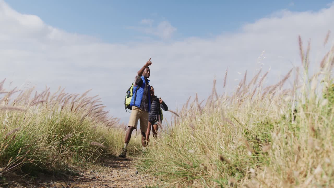 pareja afroamericana caminando mientras trekking en las montañas