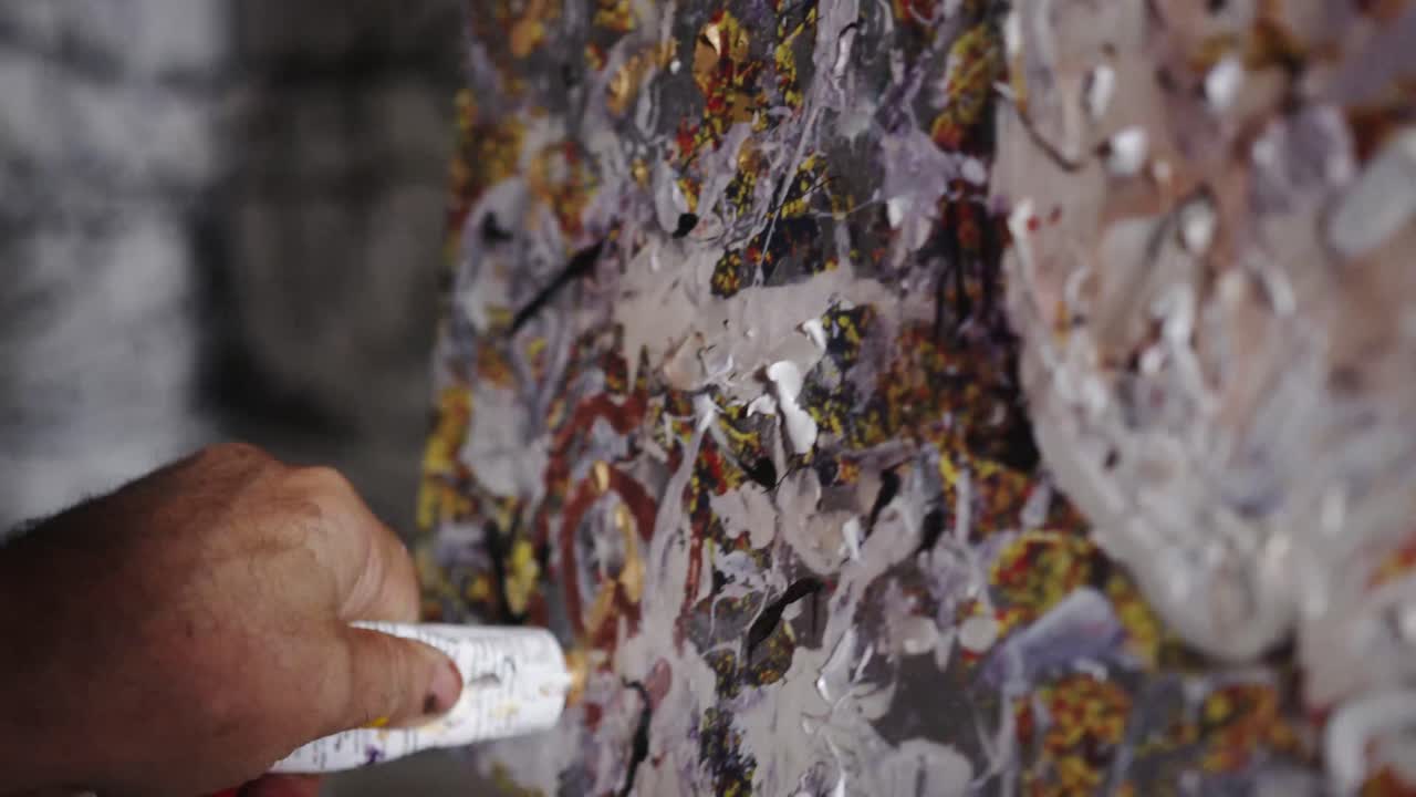 다양한 색상의 페인트로 캔버스에 그림을 그리는 아티스트