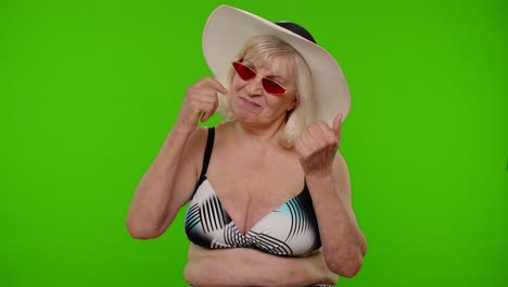 Senior-pensioner-woman-tourist-in-swimsuit-bra,-red-sunglasses-and-hat-dancing-celebrating,-smiling