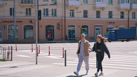 couple cross street holding hands. couple holding hands and walking at street