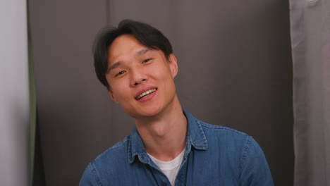 사진 부스에서 재미있는 젊은 남자가 초상화에 포즈를 취하고 실시간으로 찍은 손으로 심장 몸짓을합니다.